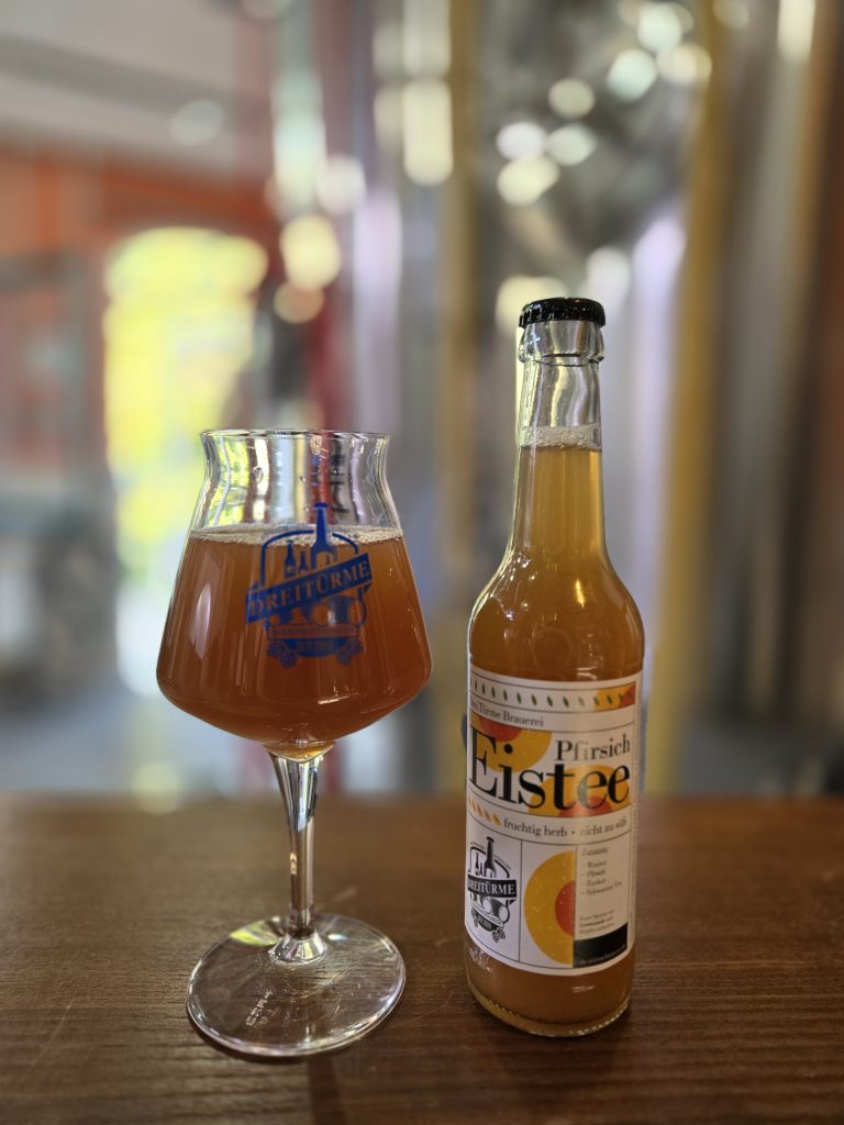 Pfirsich Eistee abgebildet in der Flasche und im Glas in der Drei Türme Brauerei